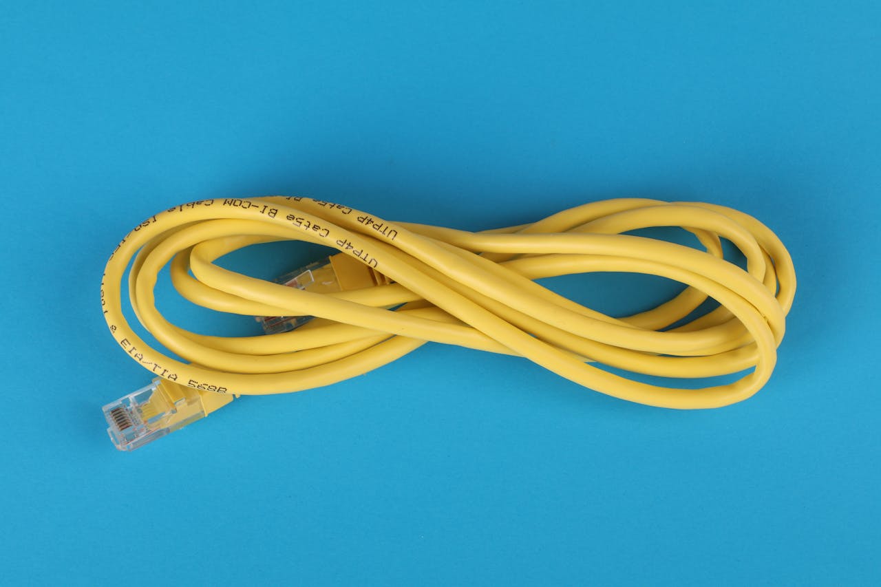 High-angle view of a yellow ethernet cable on a bright blue background.